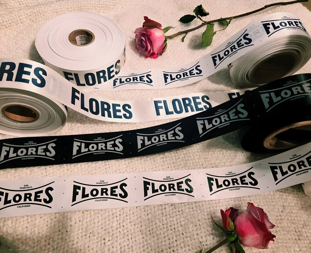 Rolls of original FLORES label tape, the San Francisco California cartouche printed in navy on white and in white on black.