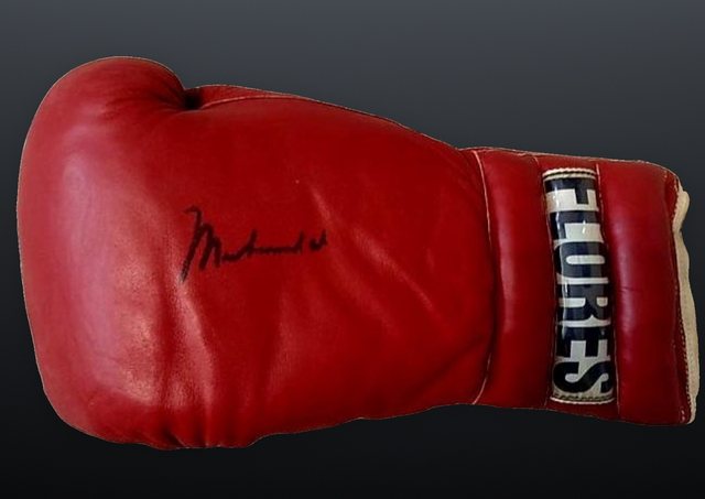 A red FLORES boxing glove signed by Muhammad Ali.