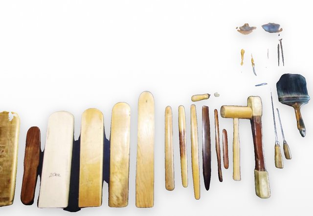 Original leatherworking tools from the FLORES bench, laid out in a row.